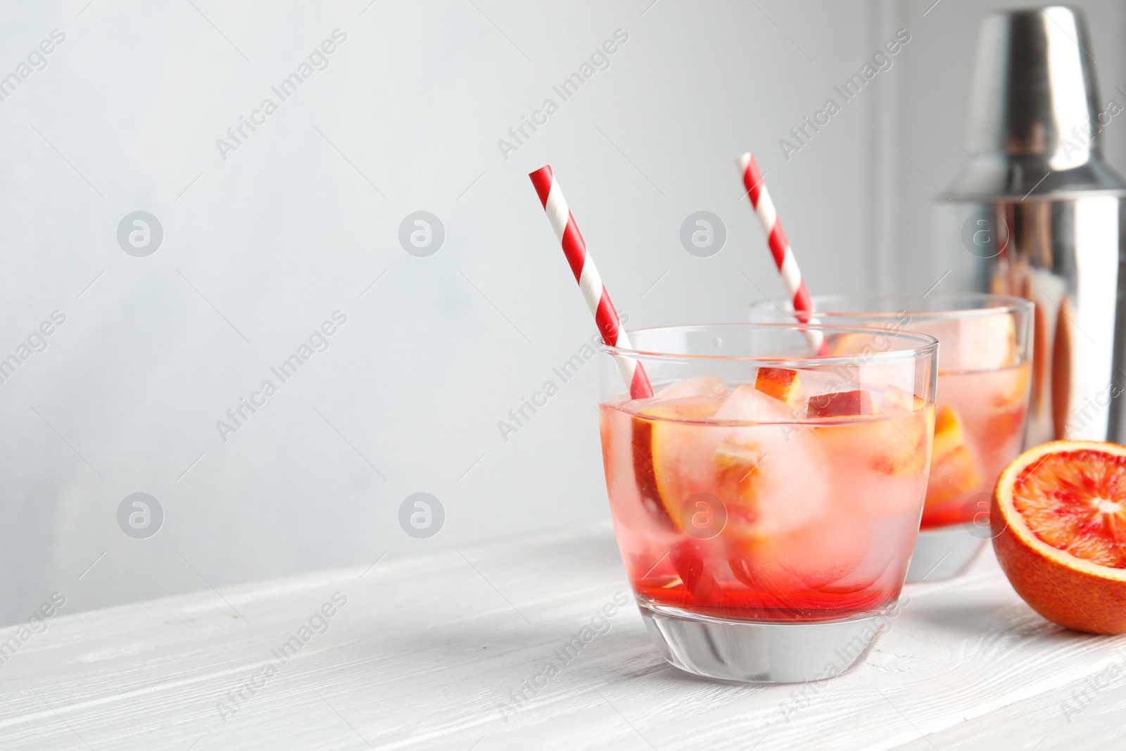Photo of Glass of tropical cocktail with ice cubes on table against light background. Space for text