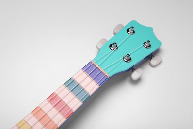 Photo of Colorful ukulele neck on white background, above view. String musical instrument