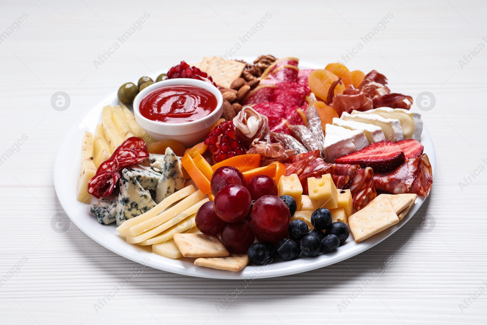 Photo of Plate of different appetizers with sauce on white wooden table, closeup