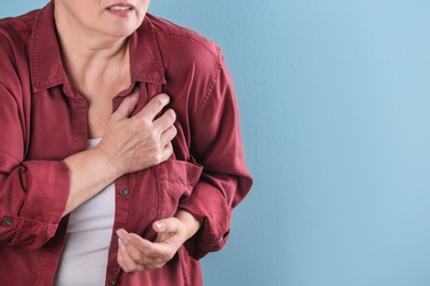 Photo of Mature woman having heart attack on color background