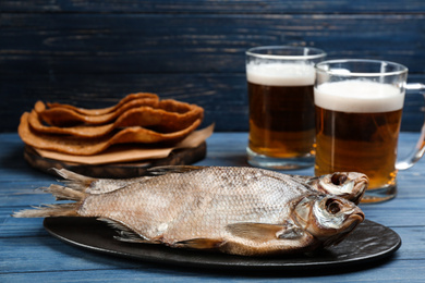 Photo of Tasty dried fish to beer on blue wooden table