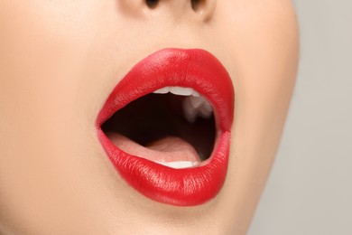 Woman with red lipstick on light background, closeup