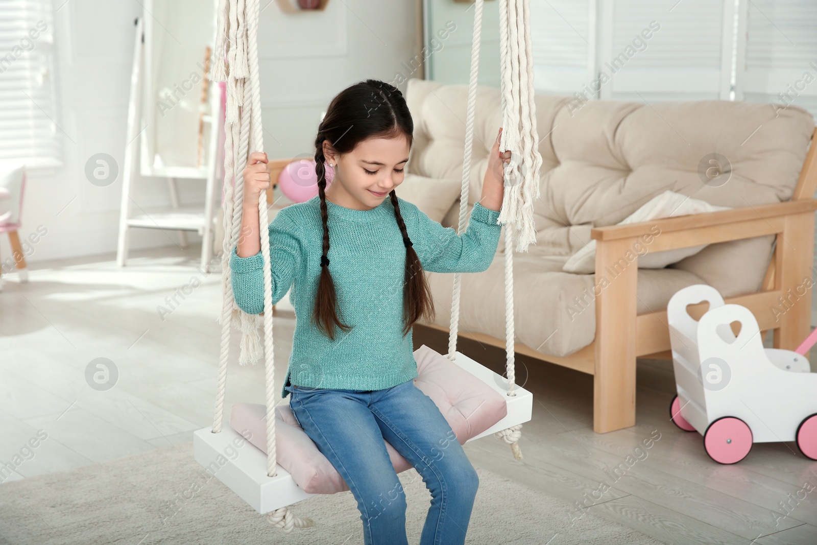 Photo of Cute little girl playing on swing at home