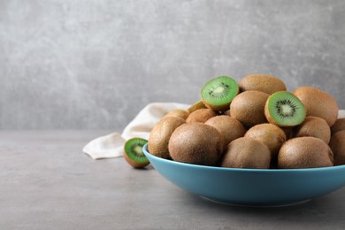 Photo of Fresh ripe kiwis in bowl on light grey table, space for text