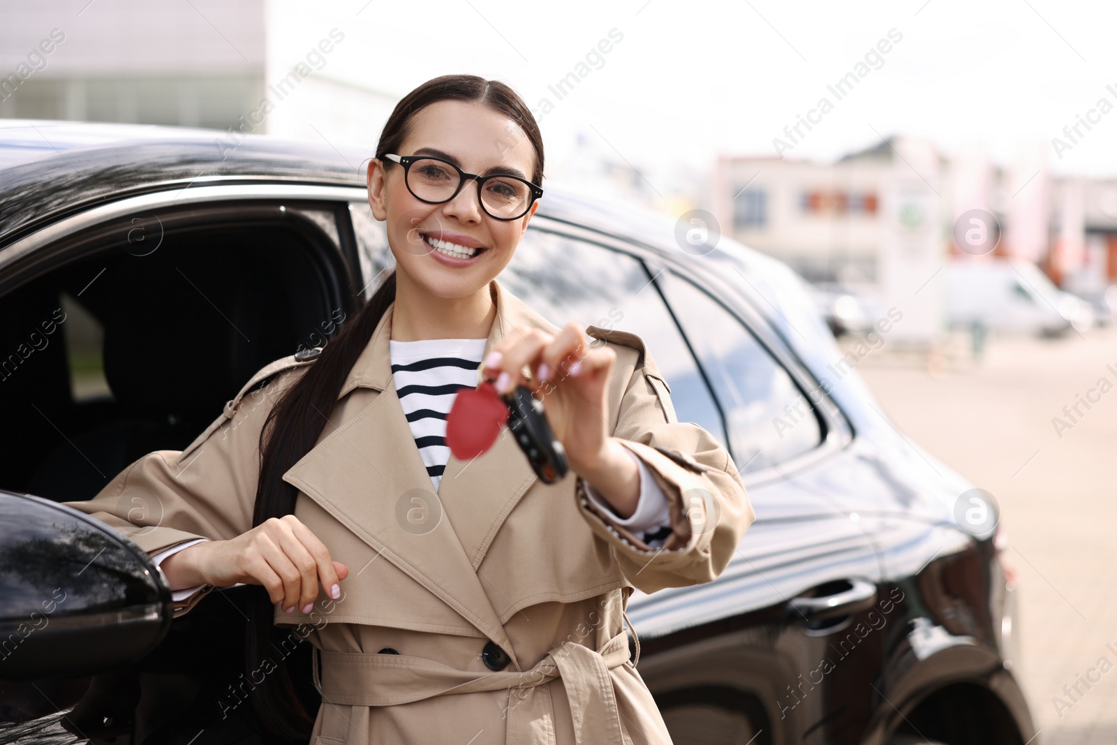 Photo of Woman holding car flip key near her vehicle outdoors