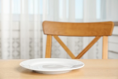 Photo of Empty white ceramic plate on wooden table