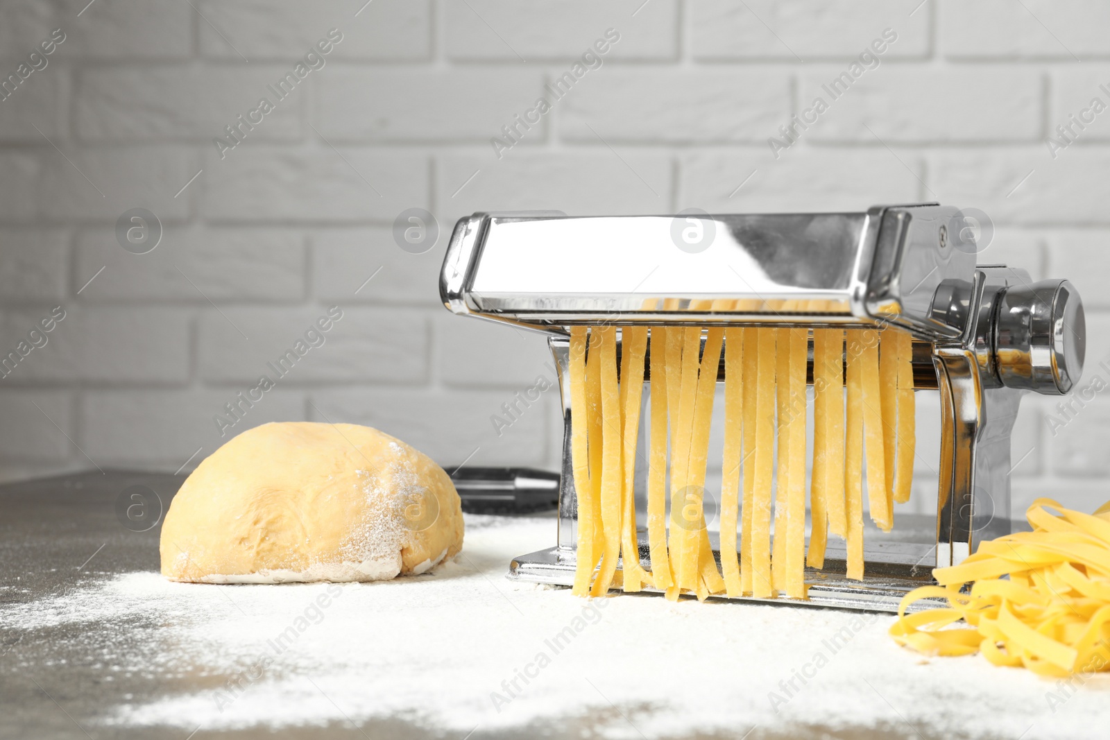 Photo of Pasta maker with dough on kitchen table