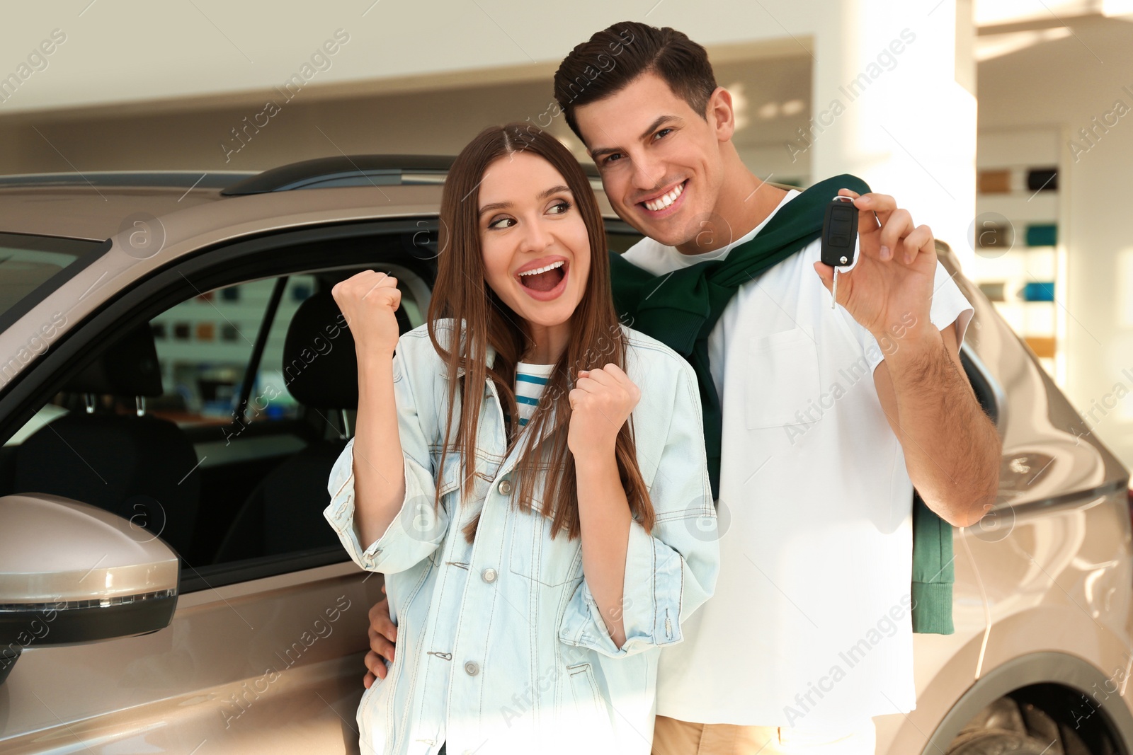 Photo of Happy couple with car key in modern auto dealership