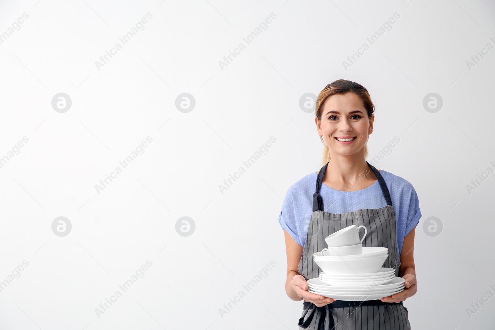 Photo of Woman with clean dishes and cups on white background. Space for text