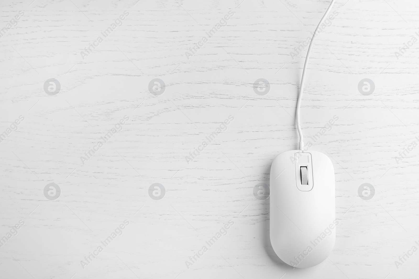 Photo of Modern wired optical mouse on white wooden table, top view. Space for text