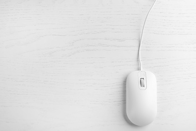 Modern wired optical mouse on white wooden table, top view. Space for text