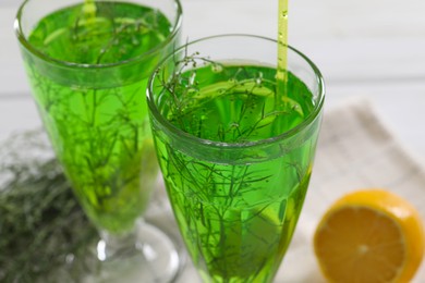 Glasses of homemade refreshing tarragon drink on table, closeup