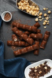 Tasty chocolate bars with nuts on black table, flat lay