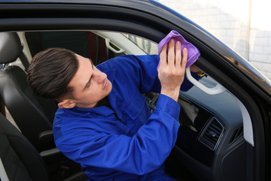 Photo of Car wash worker cleaning automobile with rag outdoors