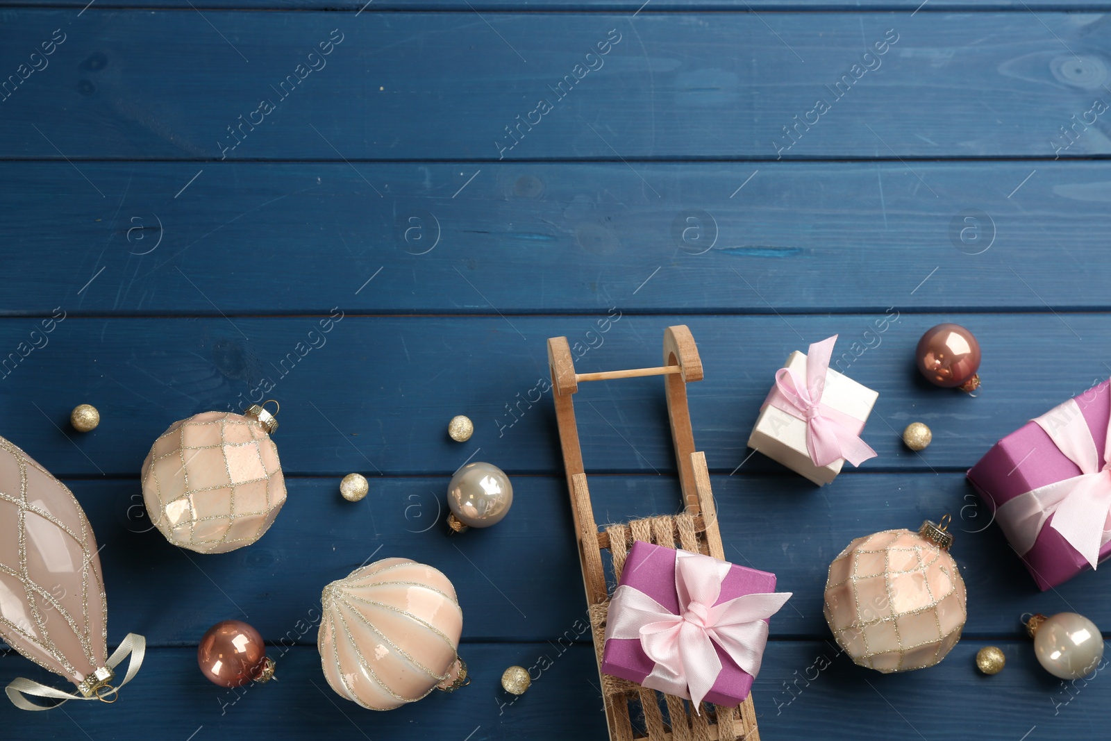 Photo of Beautiful Christmas composition with miniature sleigh on blue wooden table, flat lay. Space for text