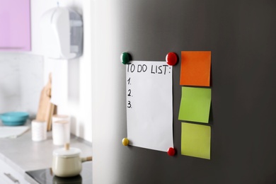 Paper notes, to-do list and magnets on refrigerator door in kitchen