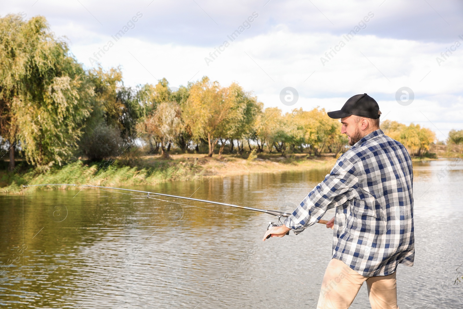 Photo of Man with rod fishing at riverside. Recreational activity