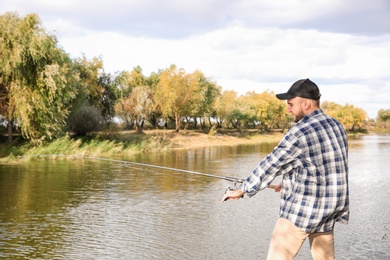 Photo of Man with rod fishing at riverside. Recreational activity