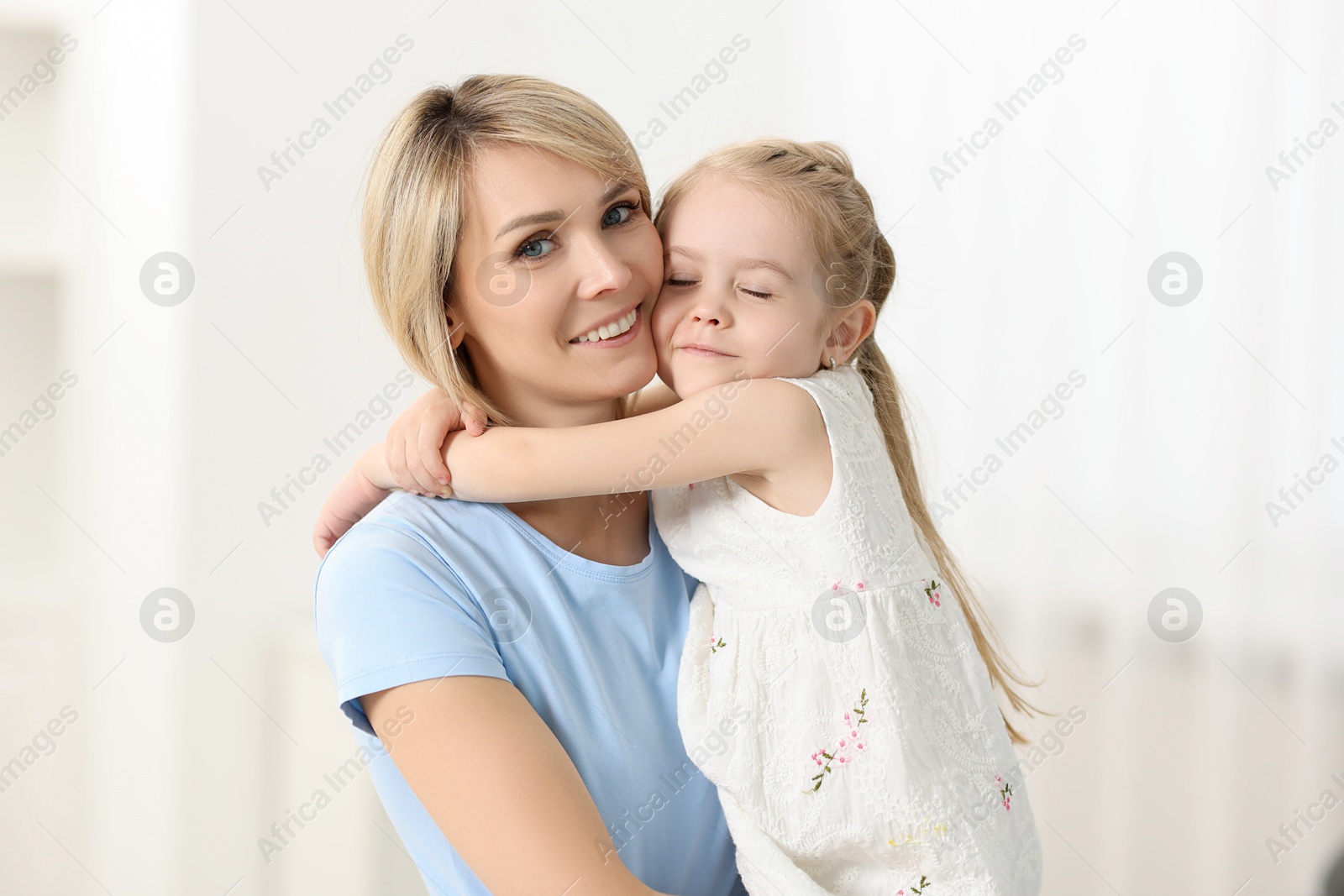 Photo of Daughter hugging her happy mother at home
