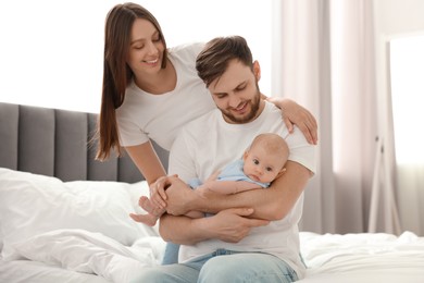 Photo of Happy family. Parents with their cute baby on bed indoors