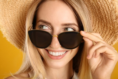 Beautiful woman in stylish sunglasses on yellow background, closeup