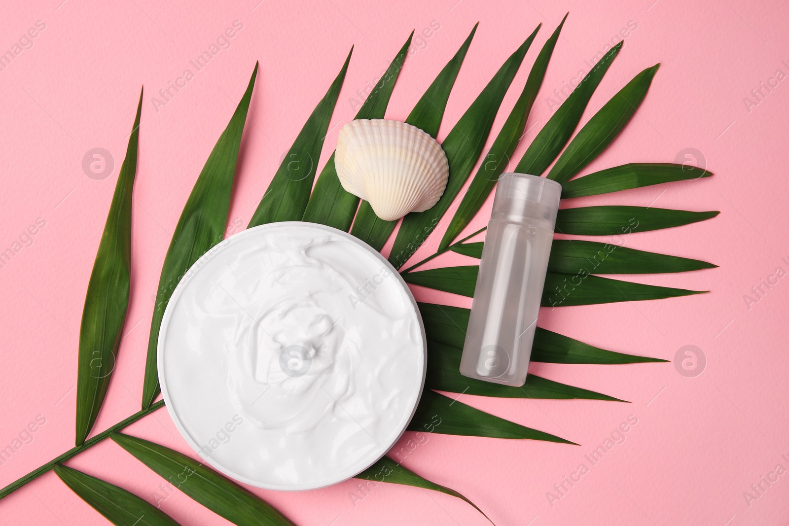 Photo of Cosmetic products, palm leaf and shell on pink background, flat lay