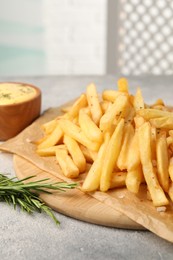 Photo of Delicious french fries served with sauce on grey textured table, closeup