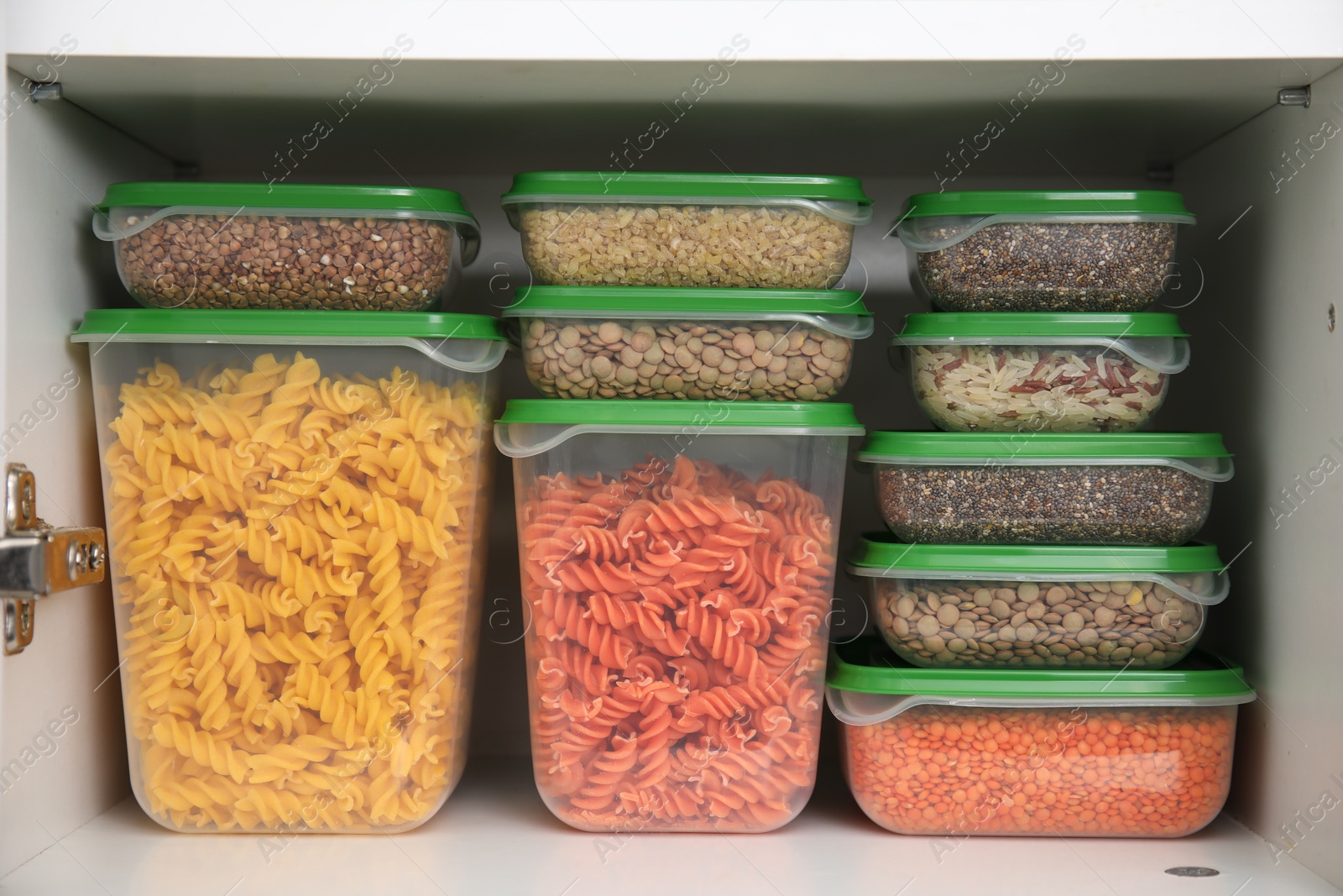 Photo of Plastic containers filled with food products in kitchen cabinet, closeup