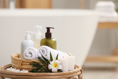 Spa products, burning candles, plumeria flower and tropical leaf on table in bathroom. Space for text