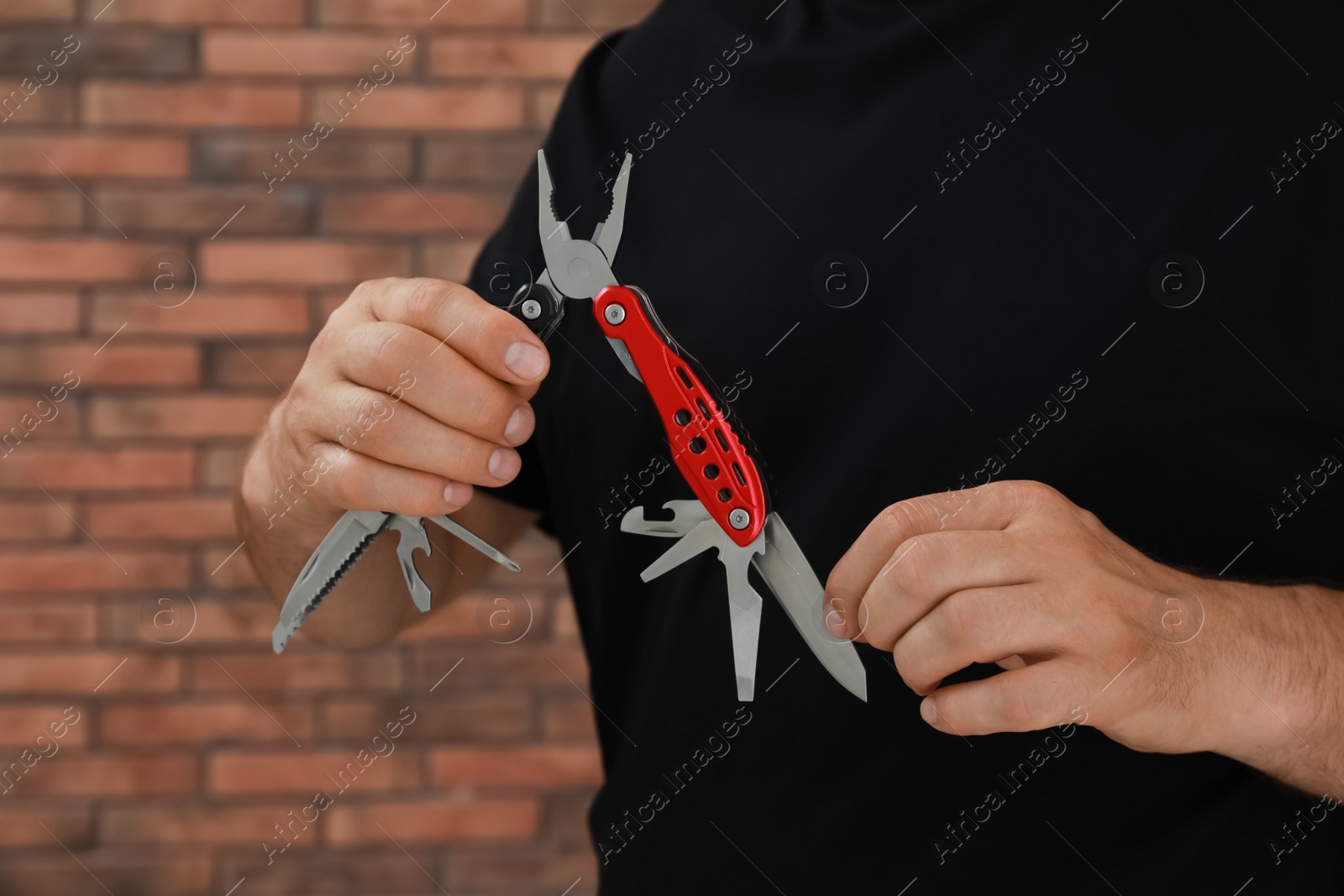 Photo of Man holding multitool near brick wall, closeup