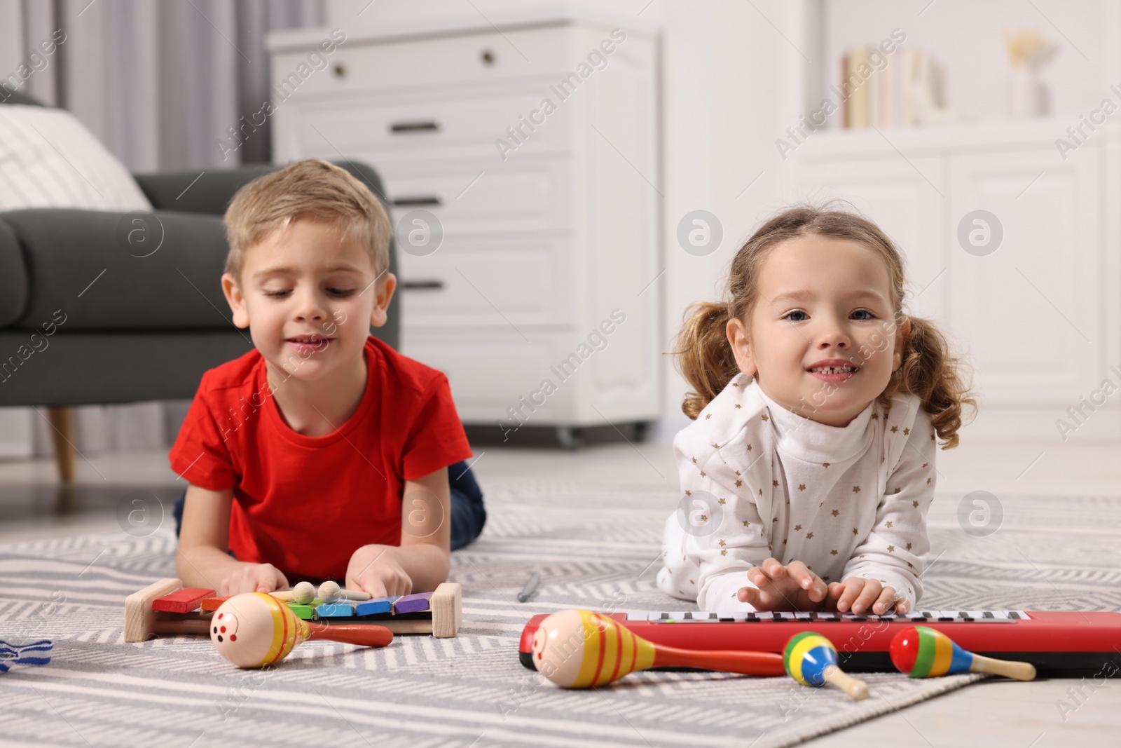 Photo of Little children playing toy musical instruments at home