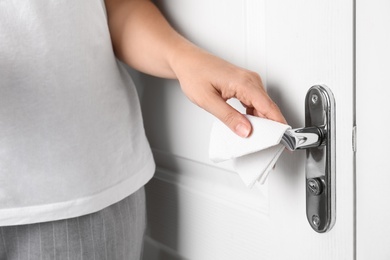 Photo of Woman using tissue paper to open door, closeup