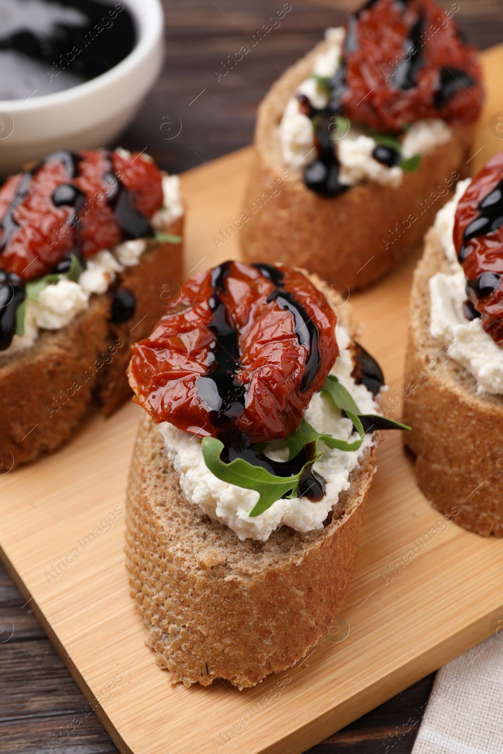 Photo of Delicious bruschettas with sun-dried tomatoes, cream cheese and balsamic vinegar on table, closeup