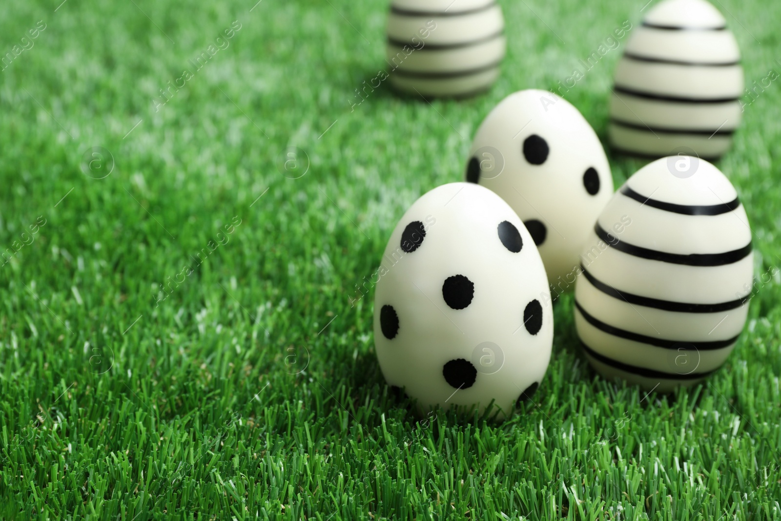 Photo of Traditional Easter eggs decorated with black paint on green lawn, space for text