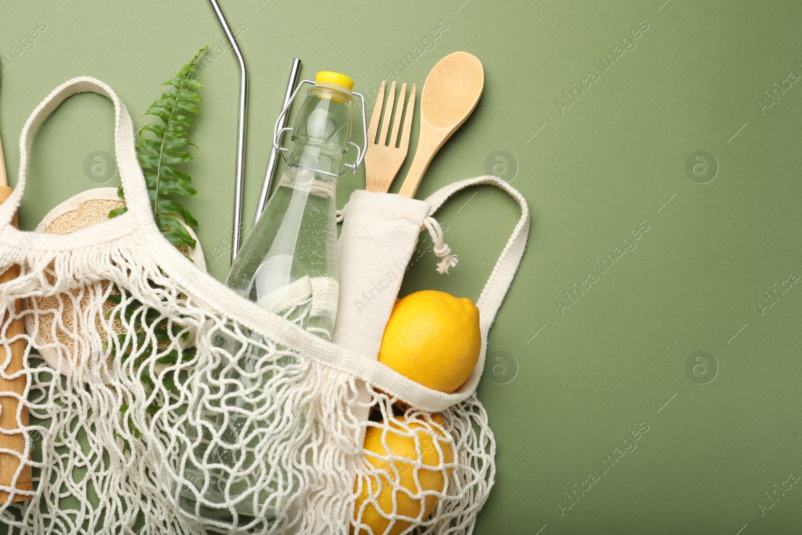 Photo of Bag with eco friendly products on green background, top view