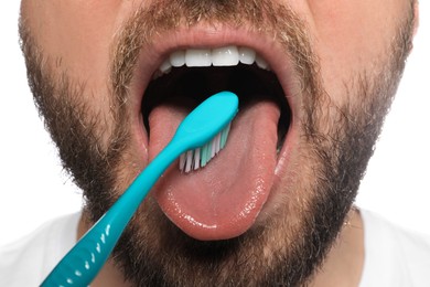 Man brushing his tongue on white background, closeup. Dental care