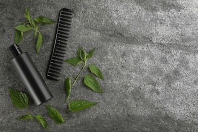 Stinging nettle, cosmetic product and comb on grey background, flat lay with space for text. Natural hair care