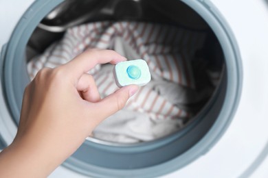 Photo of Woman putting water softener tablet into washing machine, closeup
