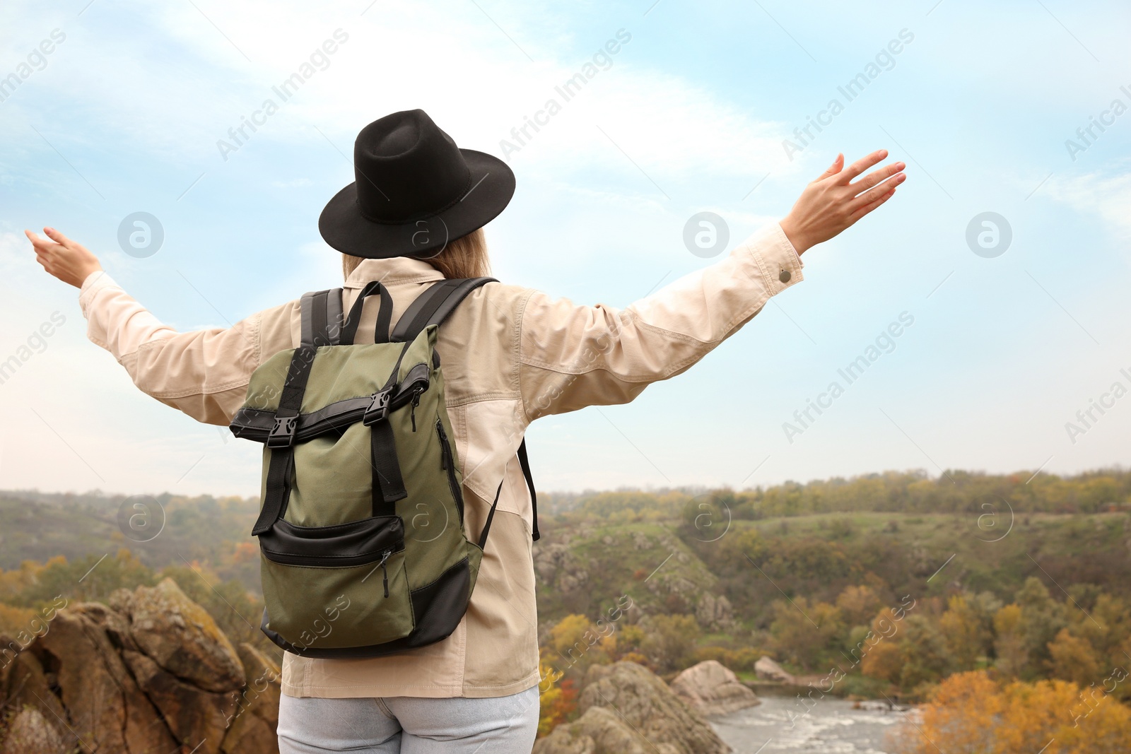 Photo of Traveler with backpack enjoying beautiful view near mountain river. Autumn vacation