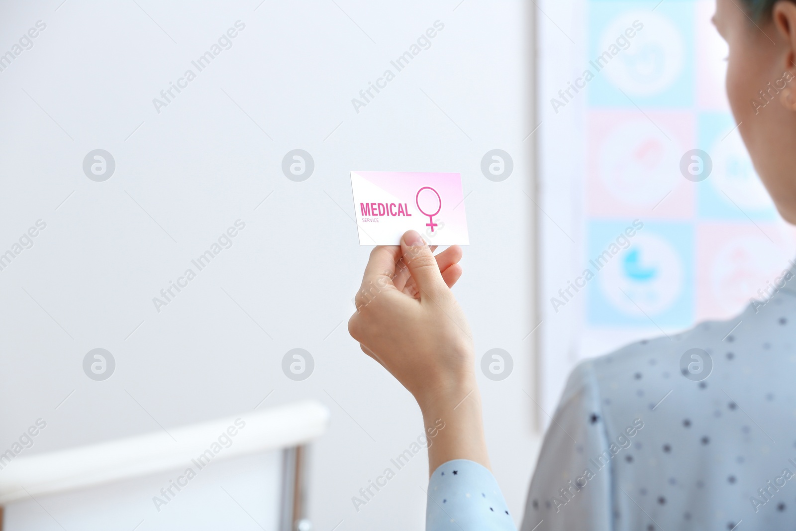 Photo of Girl holding medical business card indoors, closeup. Women's health service