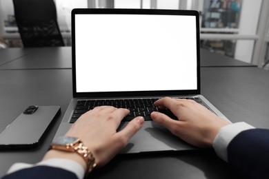 Photo of Woman working with laptop at black desk in office, closeup