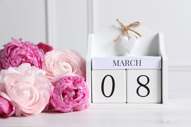 Photo of International Women's day - 8th of March. Wooden block calendar and beautiful flowers on white table