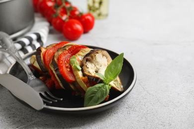 Photo of Delicious ratatouille served with basil on light grey table, closeup. Space for text