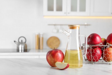 Photo of Natural apple vinegar and fresh fruits on white marble table in kitchen. Space for text