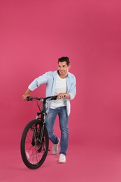 Photo of Handsome young man with modern bicycle on pink background