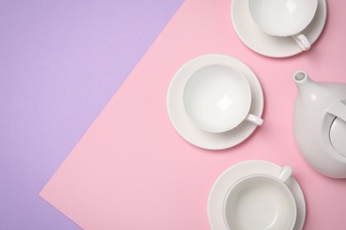 Photo of Cups with saucers and teapot on color background, flat lay. Space for text