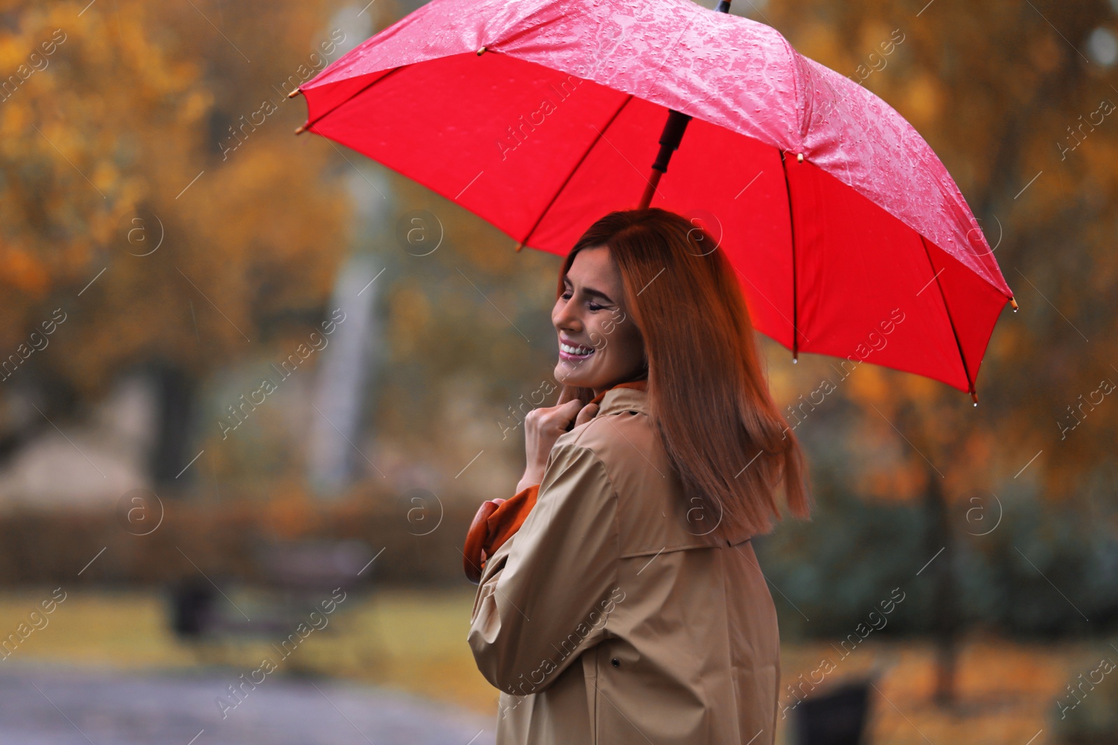 Photo of Woman with umbrella in autumn park on rainy day