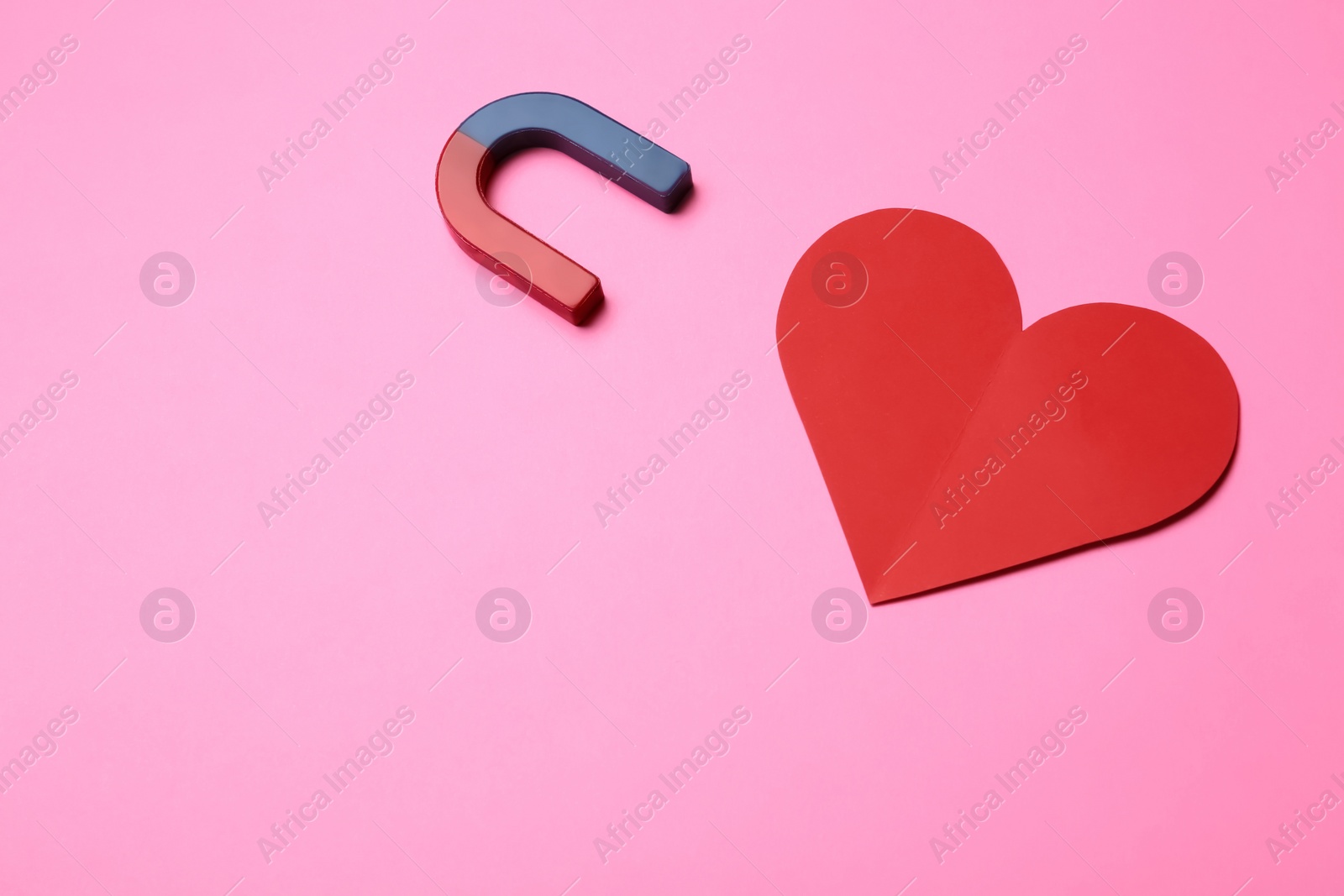 Photo of Magnet attracting red heart on color background, top view with space for text. Love concept