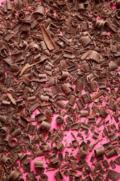 Chocolate curls on color background, top view