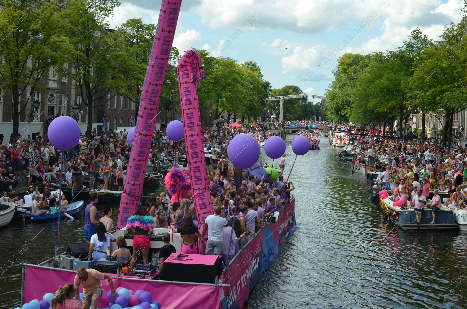 Photo of AMSTERDAM, NETHERLANDS - AUGUST 06, 2022: Many people in boats at LGBT pride parade on river